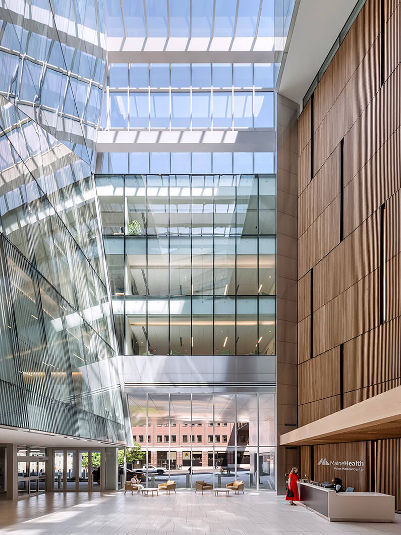 Modern lobby of Maine Medical Center showcasing sleek glass architecture and natural light.