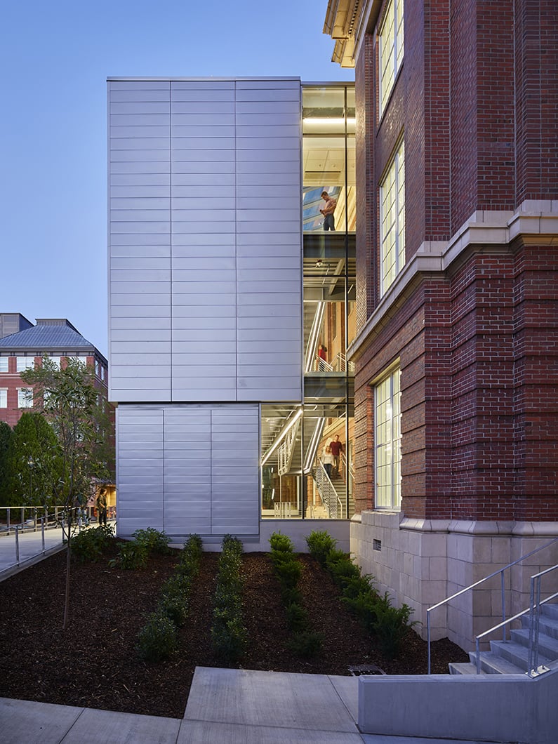 New glass addition juts out from historic building with views to interior stair and atrium