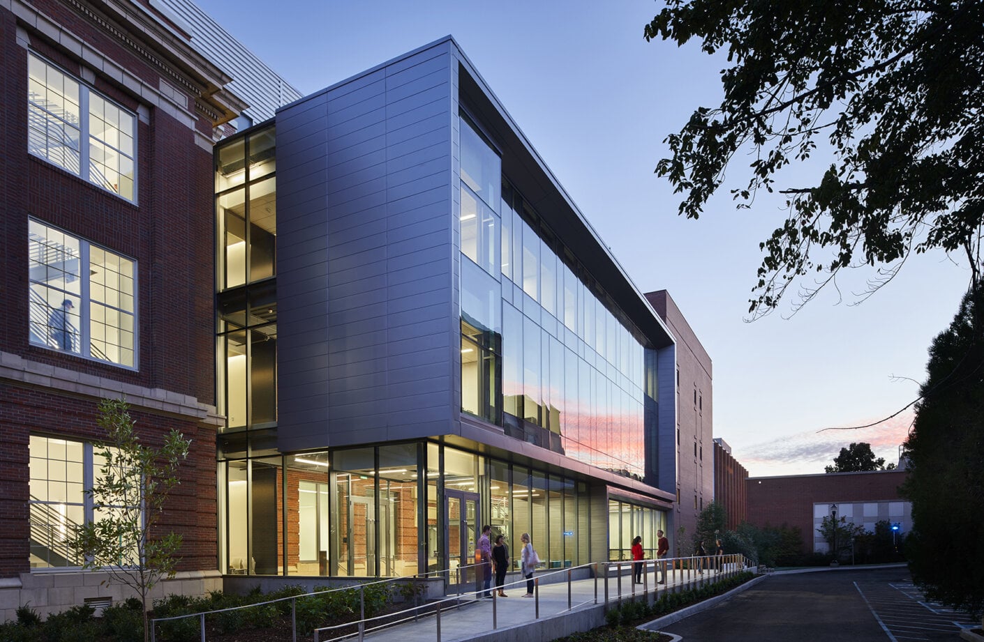 North facade of Troy Hall with glass box atrium and students gathered in front of doors along sidewalk.