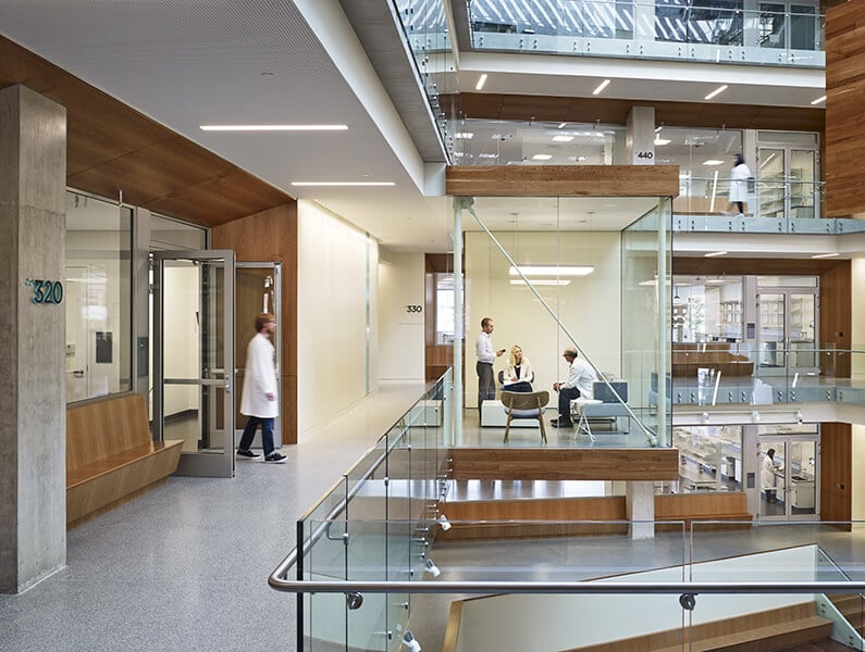 Employees conversing in collaboration pod that juts out into the atrium of the Allen Institute