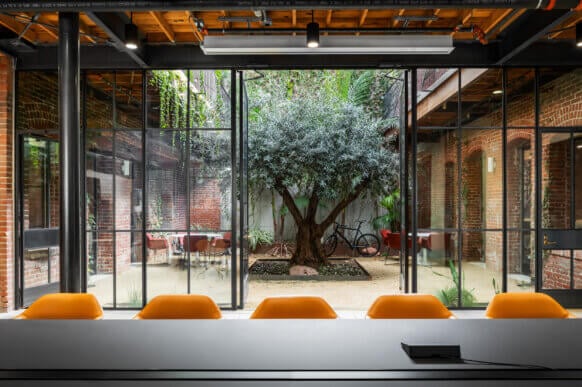 Modern meeting room with garden view and orange chairs.