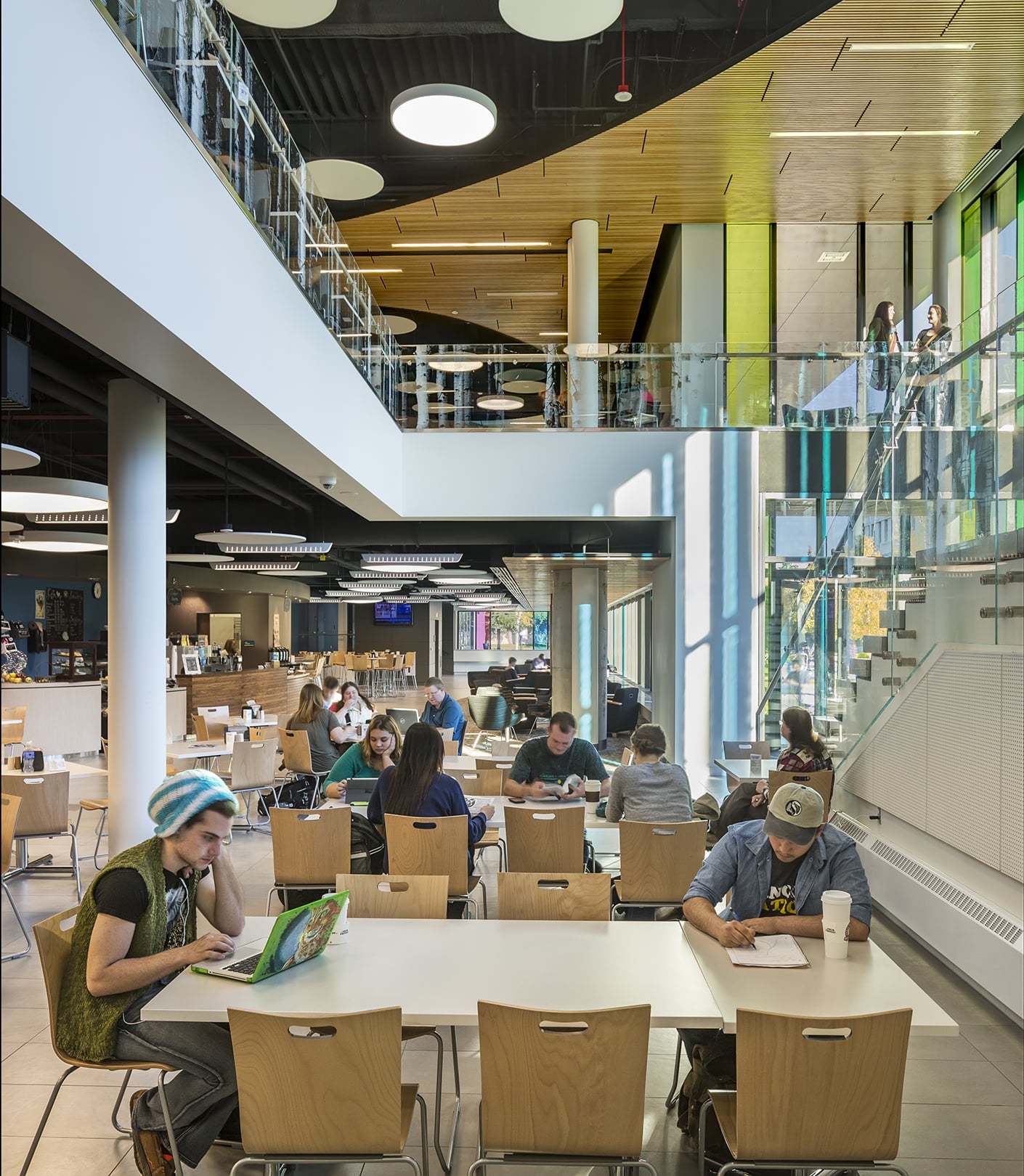 Cafeteria with students scattered throughout, eating and studying.
