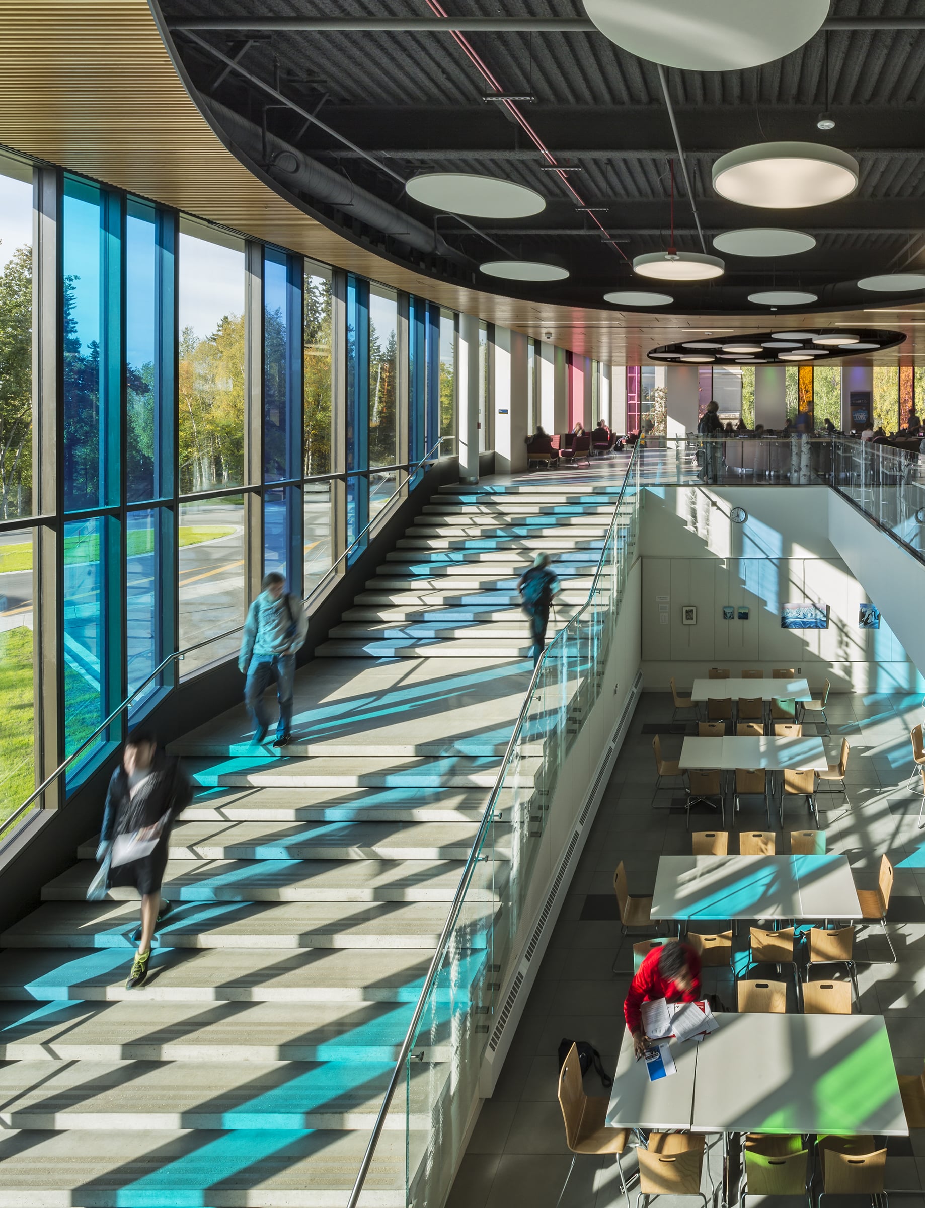 Cafeteria with large stairs and bright blue and green shadows casting on the floor