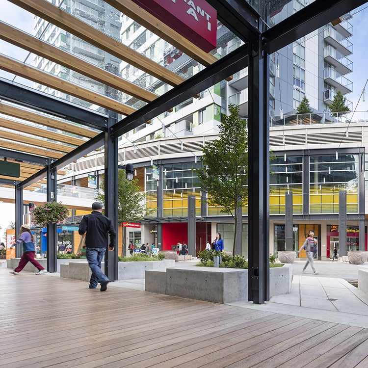 Modern urban plaza featuring sleek buildings, wooden beams, and landscaped greenery.