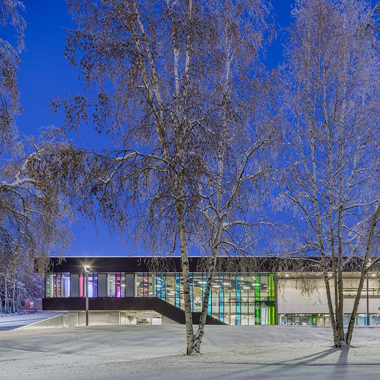 University of Alaska Fairbanks Wood Center at dusk with snow on the ground and trees
