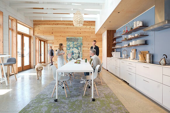 Modern kitchen with people and dog, featuring wooden walls and blue accents.