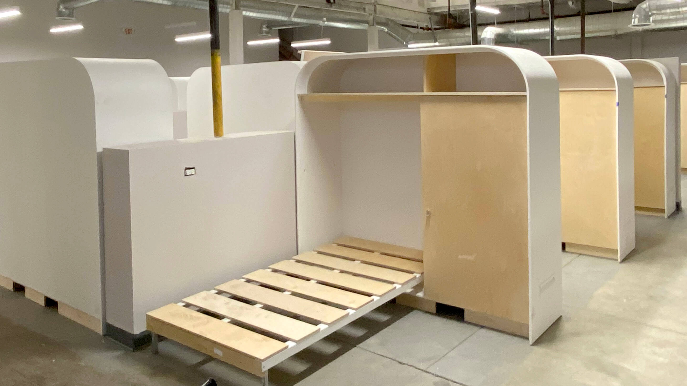 Photo showing modular temporary indoor shelter with bed and lockable storage
