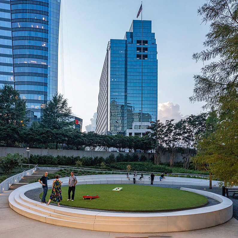 People take a break from playing cornhole on the elliptical lawn in the AFC courtyard