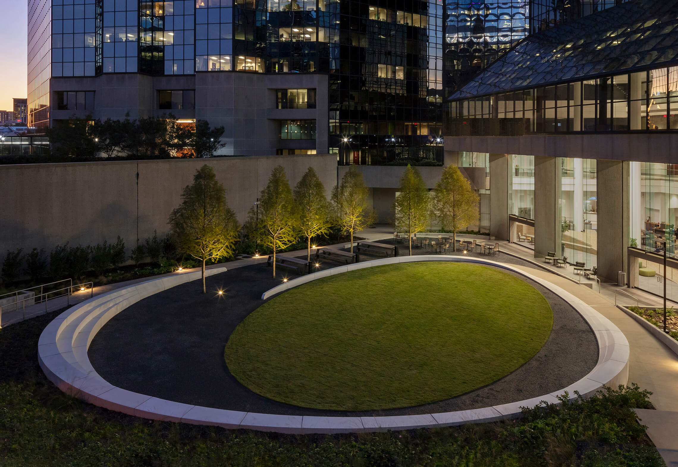 Looking into the lighted sculptured seating wall and elliptical lawn of the Atlanta Financial Center courtyard at night