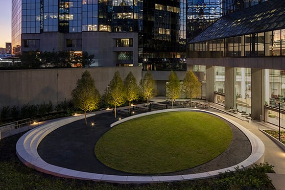 Looking into the lighted sculptured seating wall and elliptical lawn of the Atlanta Financial Center courtyard at night