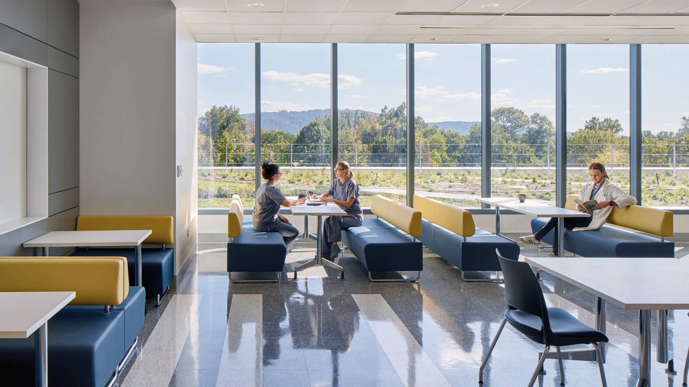 Photo showing hospital staff break room with large windows and distant views of trees and a natural landscape