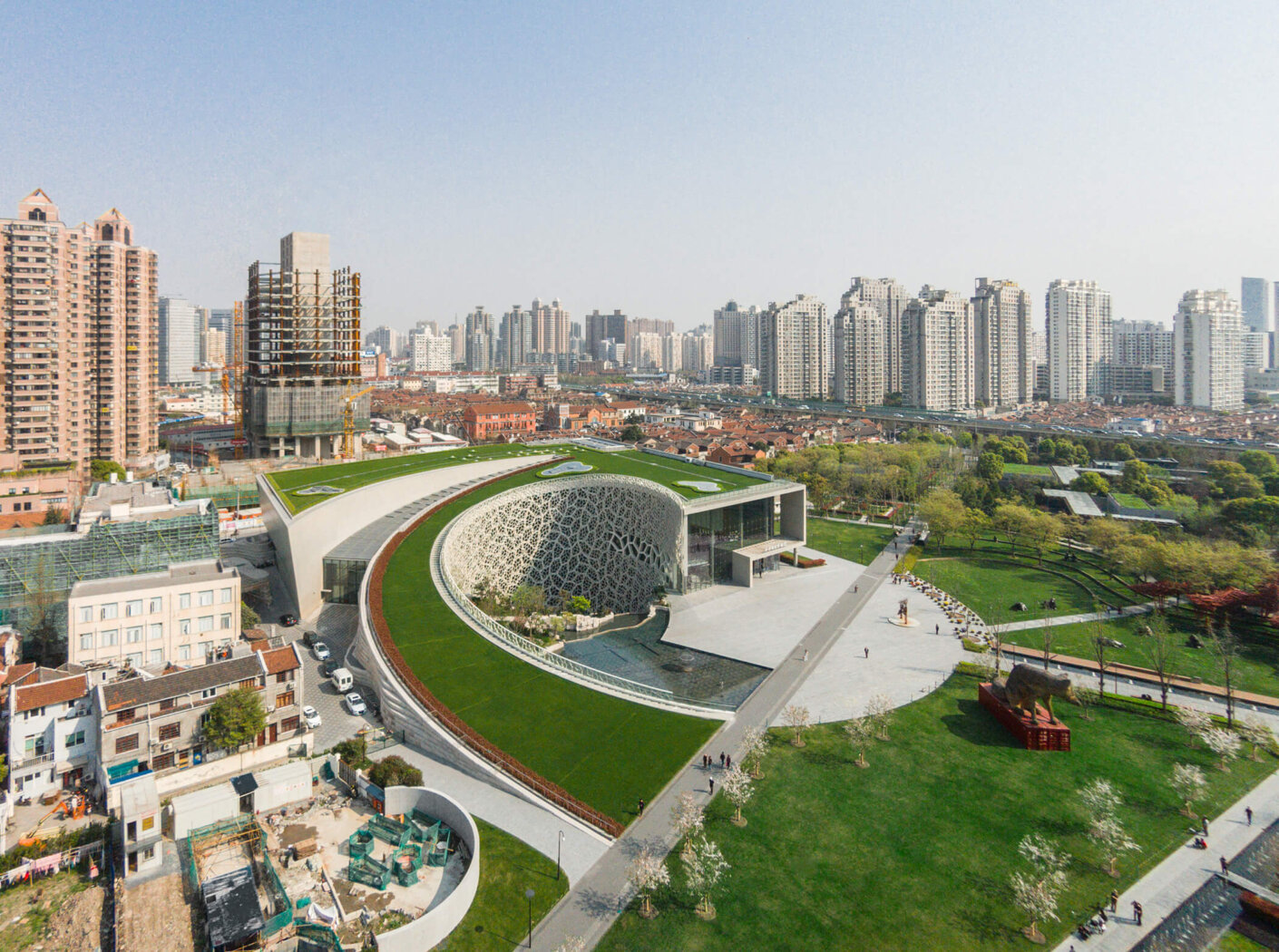 Aerial view looking down on the Shanghai Natural History Museum's spiral shape against the backdrop of the city