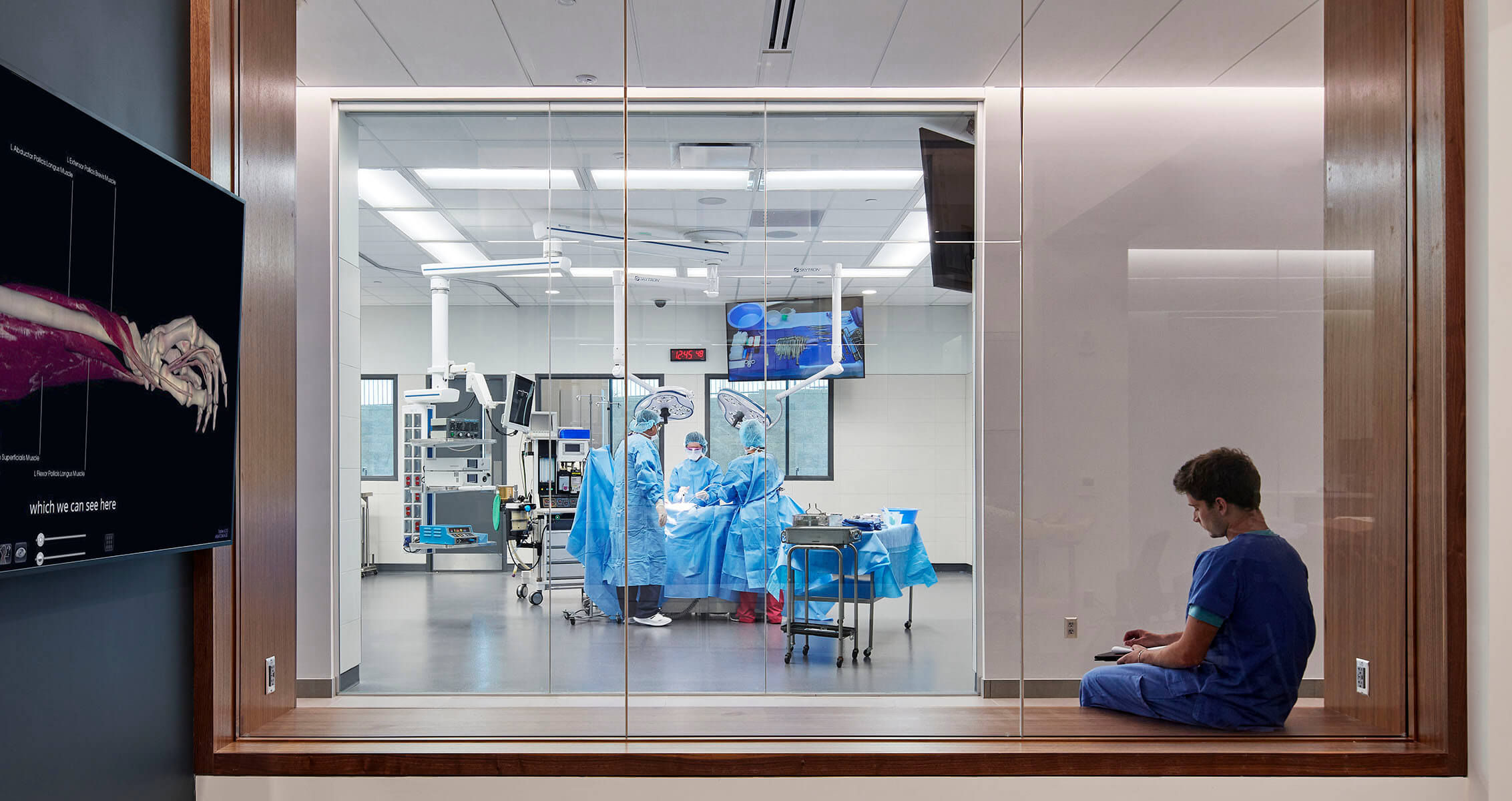 Photo of a student working with a view into a surgical simulation suite at a community college