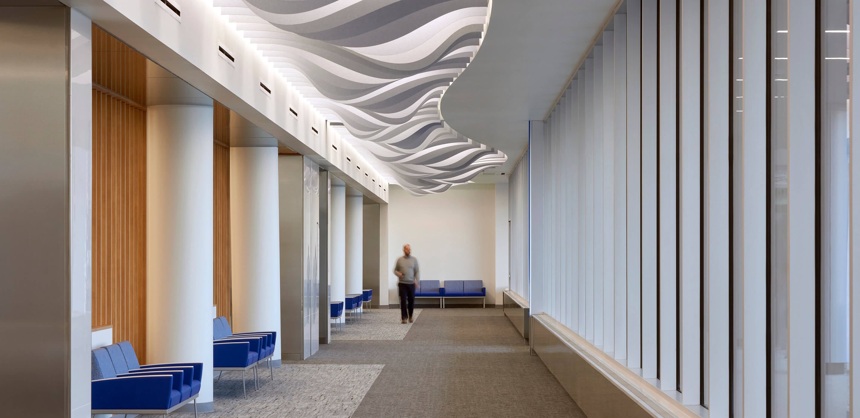 person walking down a corridor with decorative ceiling