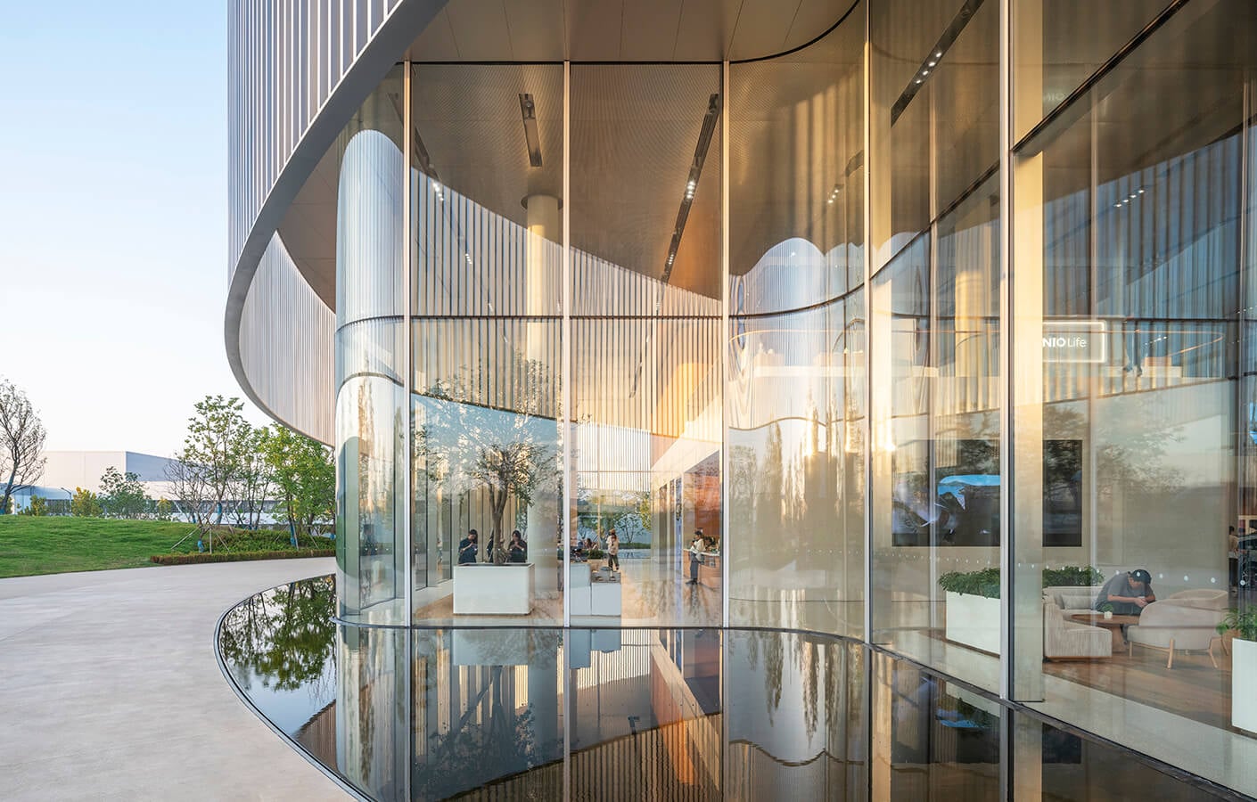 A glass wall and water feature as seen from the sidewalk outside of an electric vehicle showroom