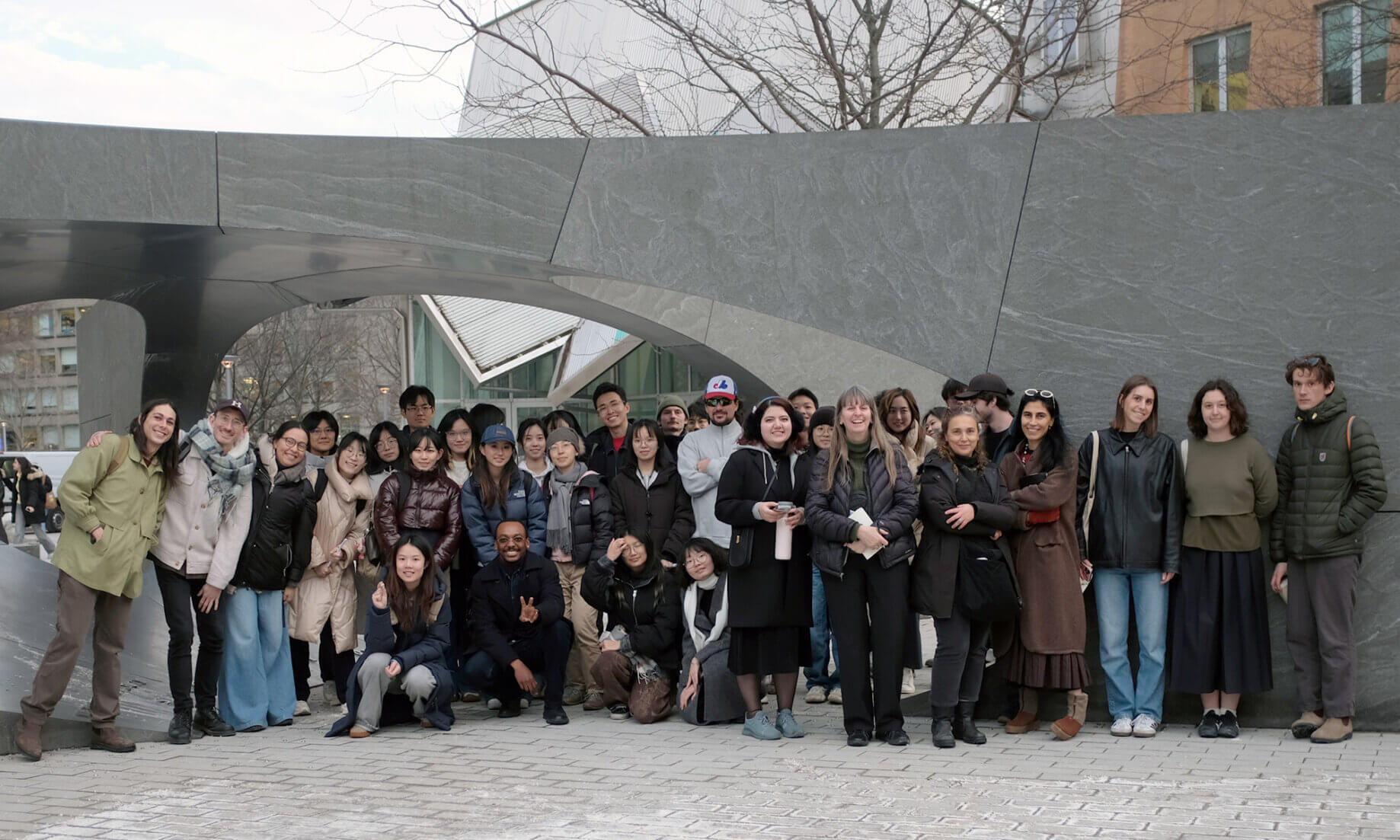 a large group of students posing under an outdoor arch