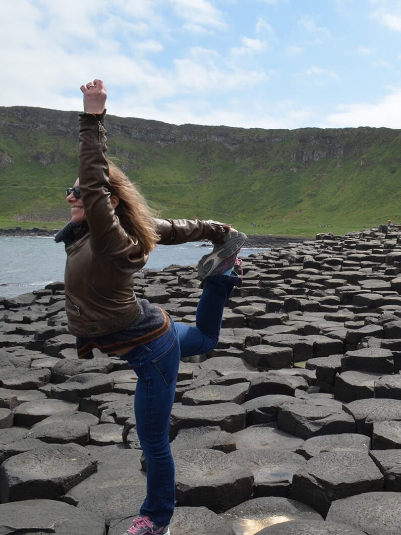 a person striking a dancer’s pose on a lakeshore