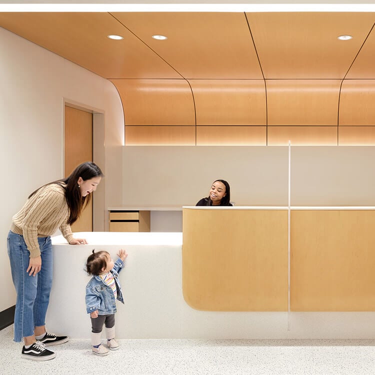 Woman and child at reception in modern reception area with wood paneling.