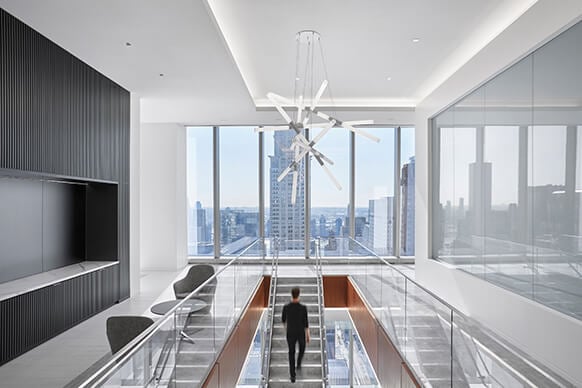 person walking up stairs with views to NYC out a window
