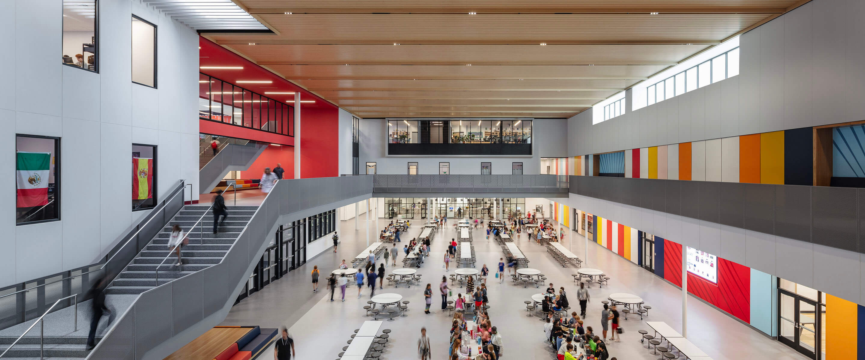 Modern school atrium with colorful walls and bustling cafeteria scene.