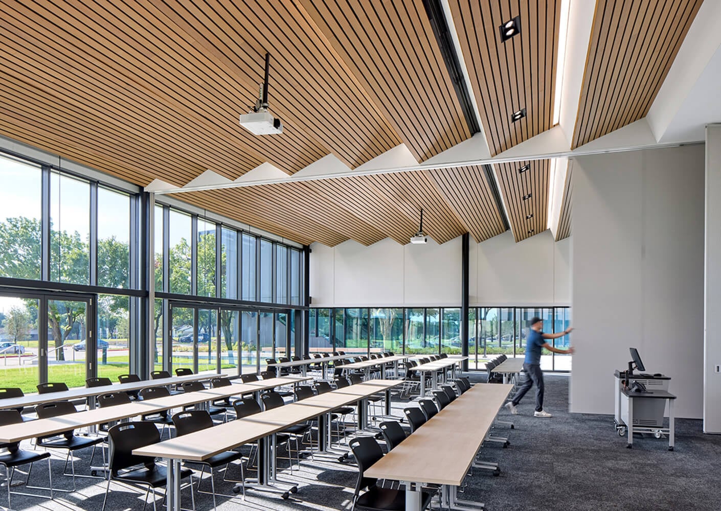 Modern classroom with wooden ceiling, large windows, and flexible seating arrangement for collaborative learning.