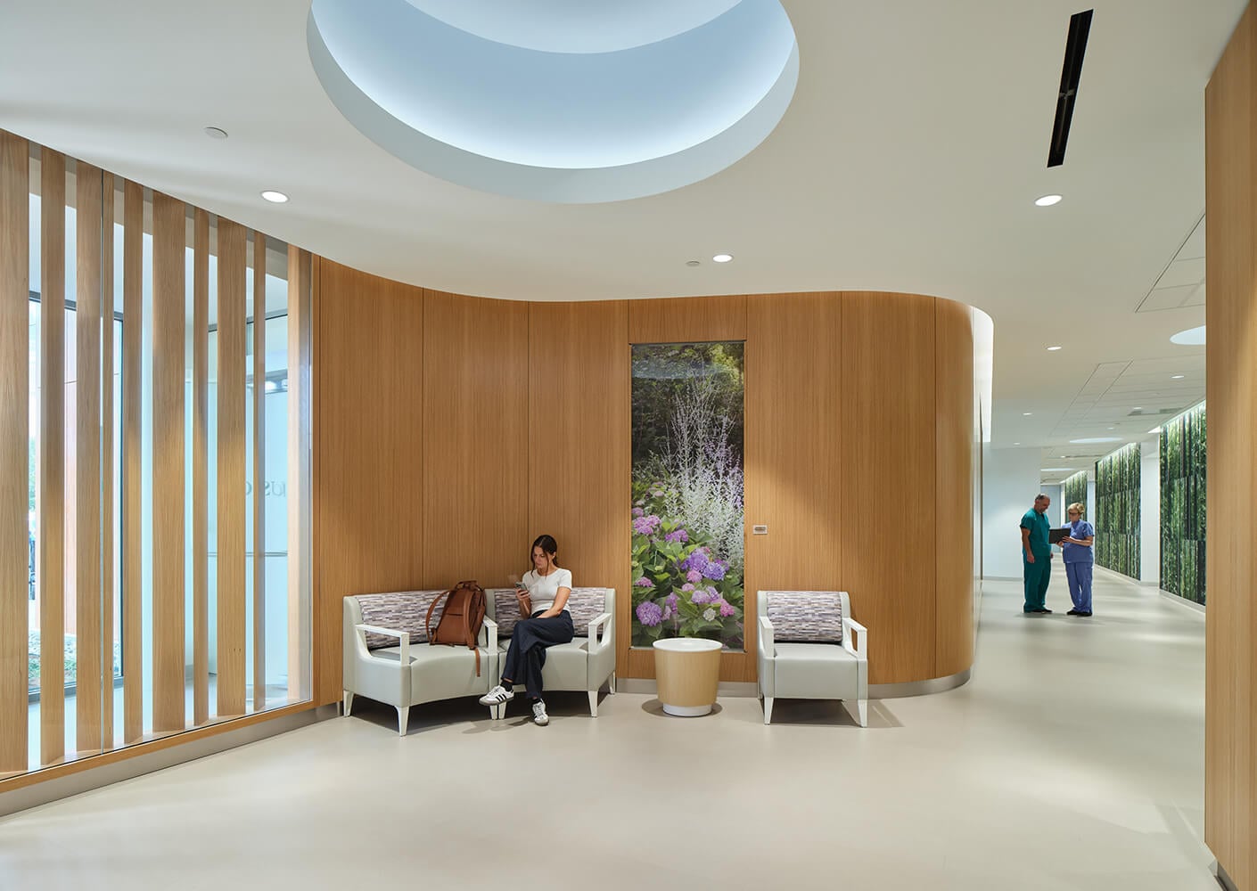Modern clinic waiting area with wooden accents, seating, and a hallway lined with nature images.