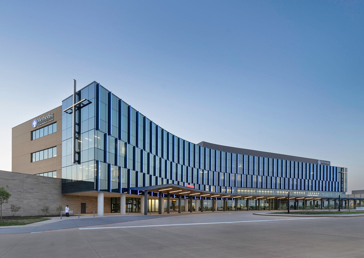 Modern hospital building with pronounced mullions and glass facade at sunset.