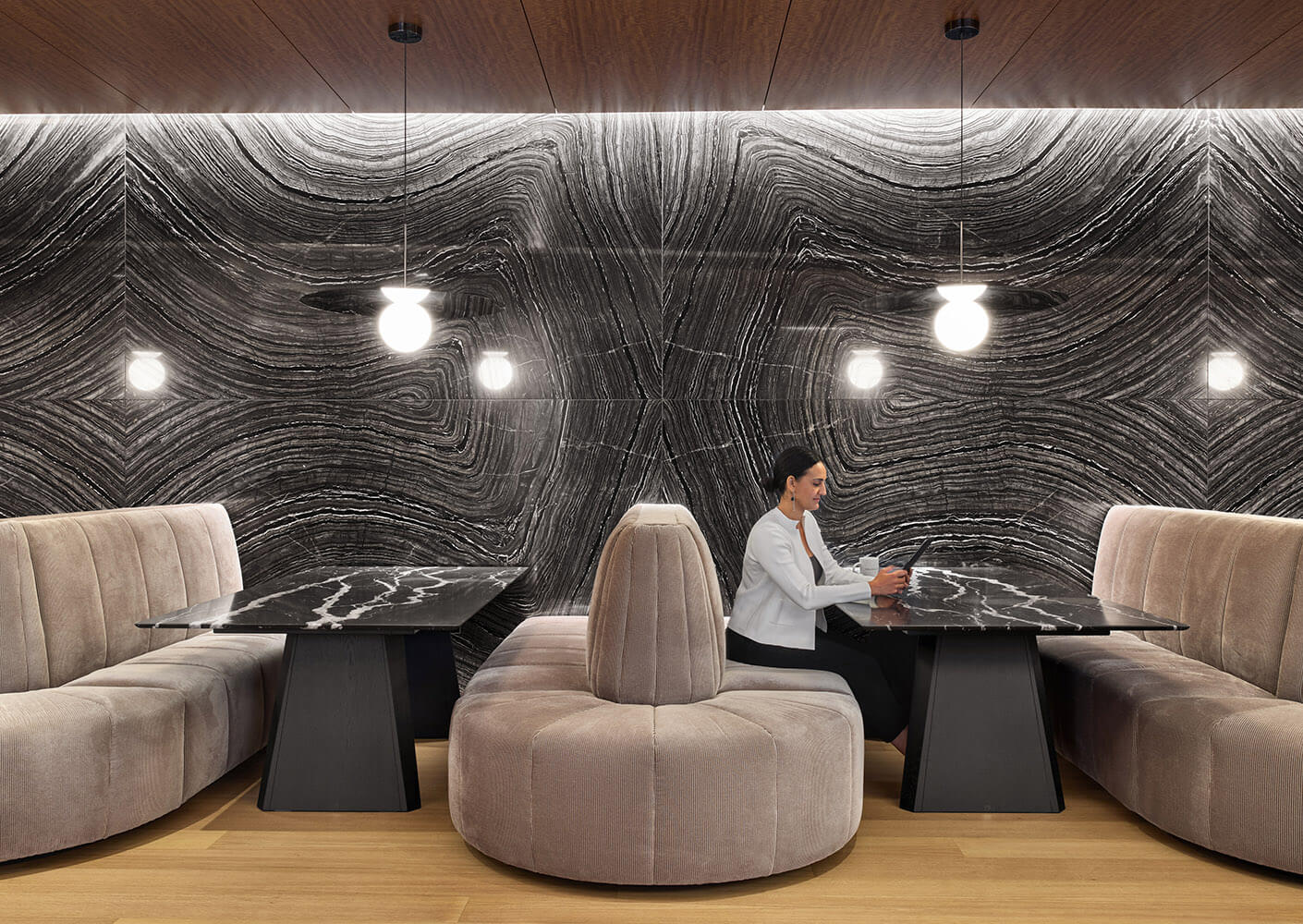 Modern lounge area with marble tables, plush seating, and abstract wall design.