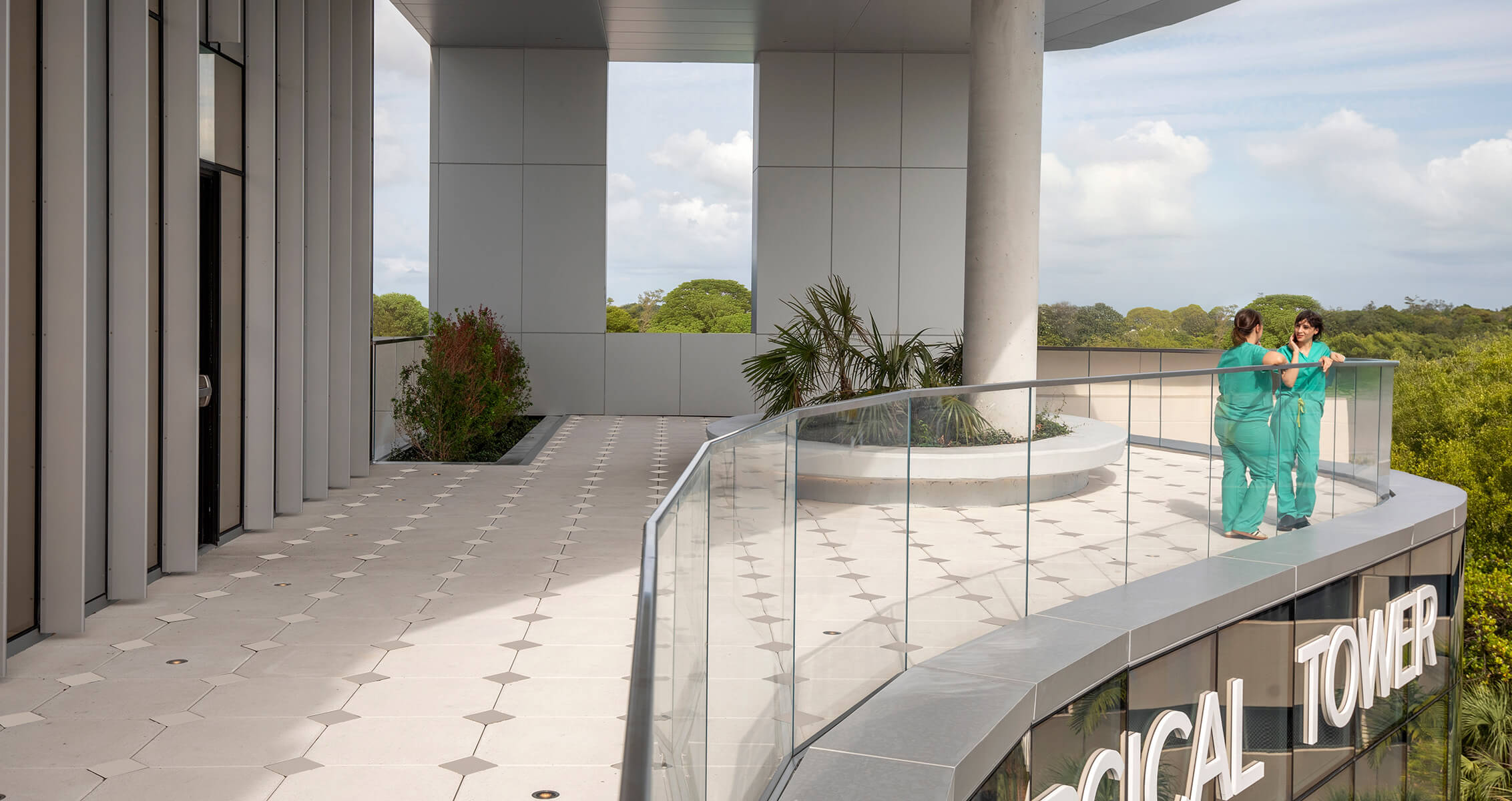 Two colleagues on a spacious white terrace with plants and tall architectural features