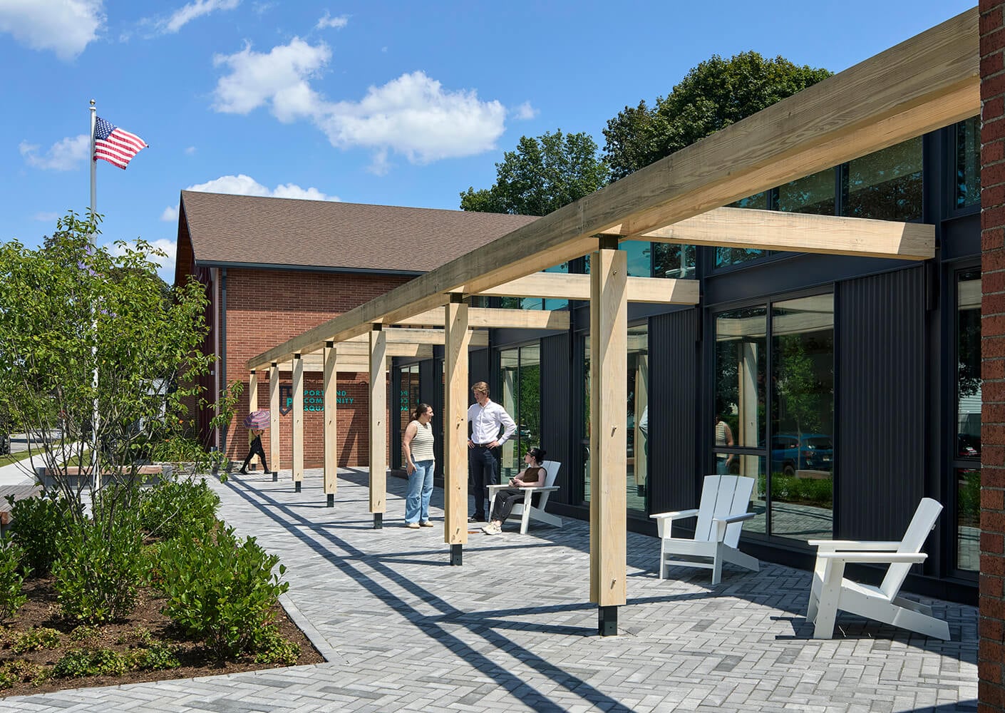 Squash community center with outdoor seating and visitors under a wooden pergola.