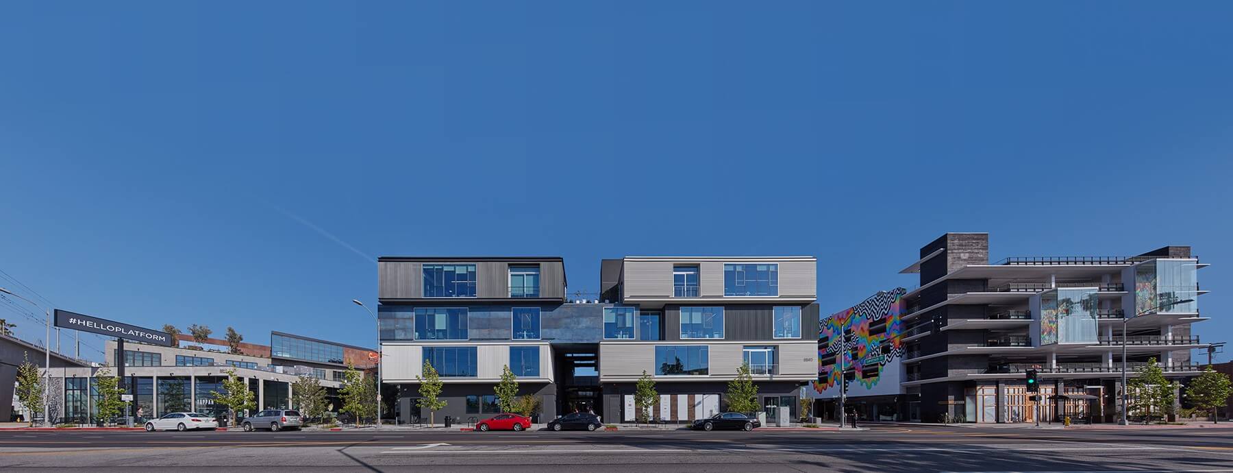 Modern urban street with contemporary buildings and bright blue sky.