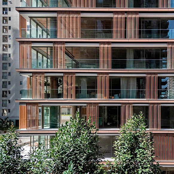 Modern building facade with wooden accents and glass balconies.
