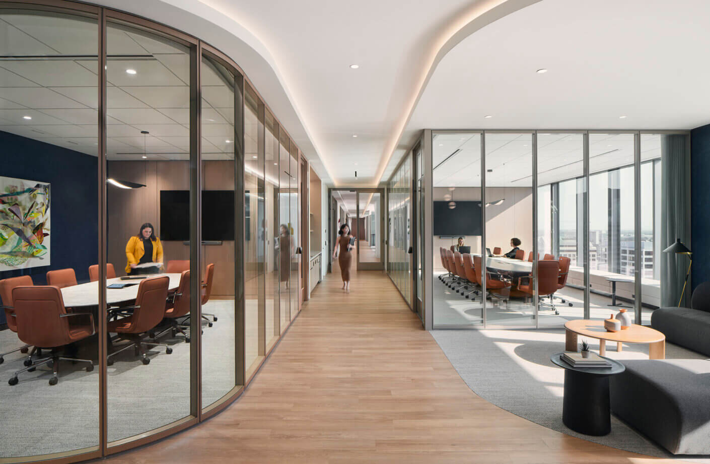 Modern office with glass-walled meeting rooms and stylish furniture.