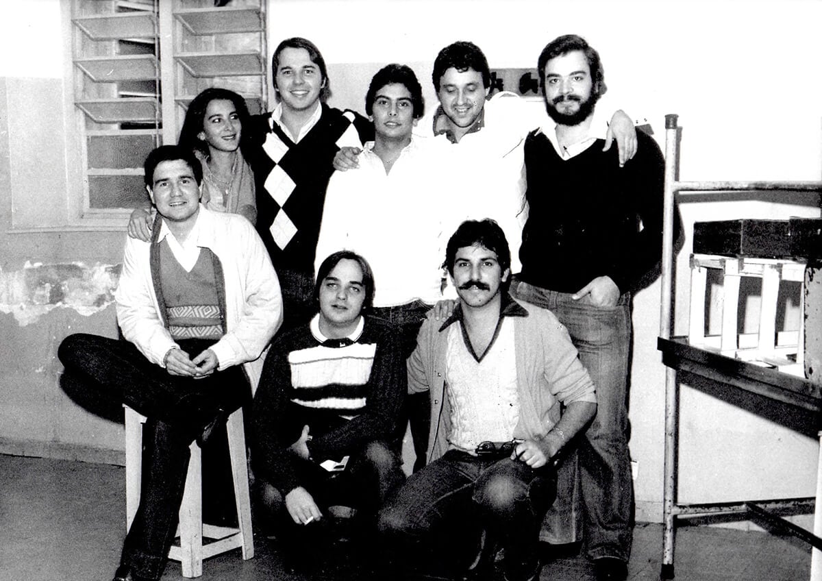 Group of young adults in a vintage black and white classroom photo.