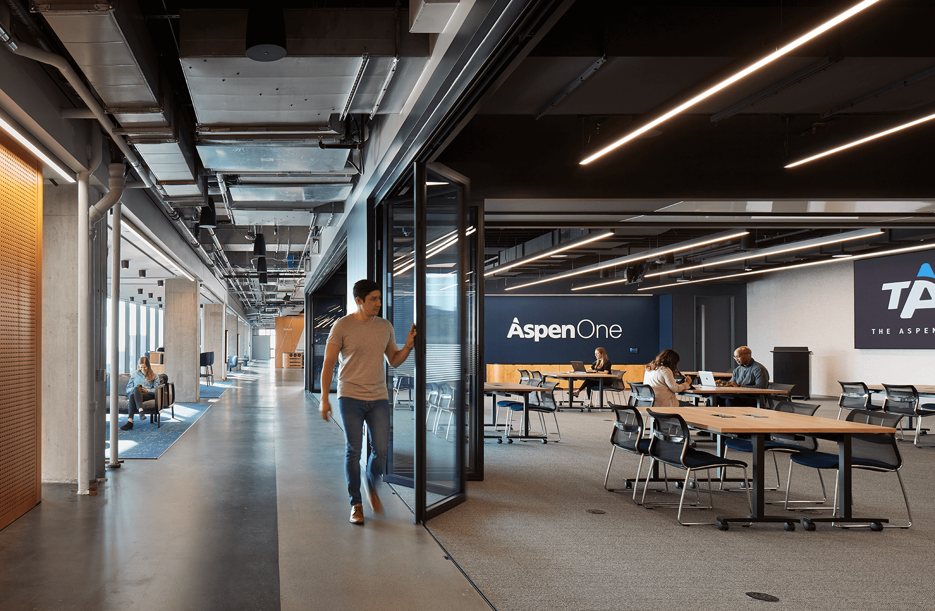 Modern office space with people working at shared tables.