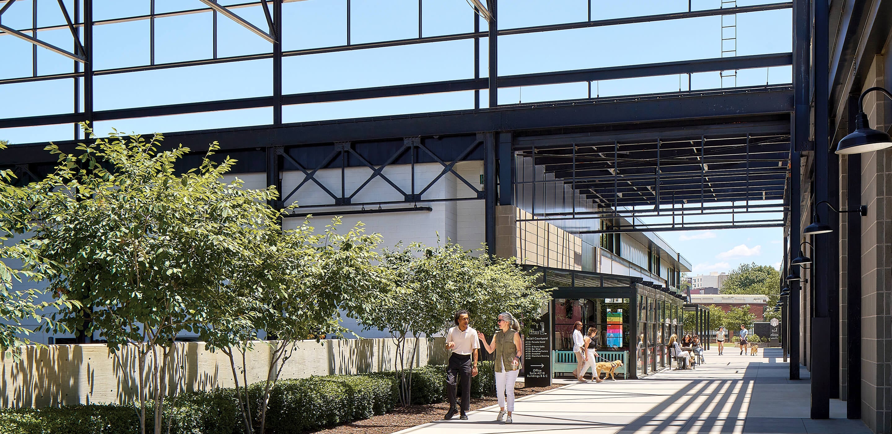 Open converted industrial space with walkway and people enjoying a sunny day.