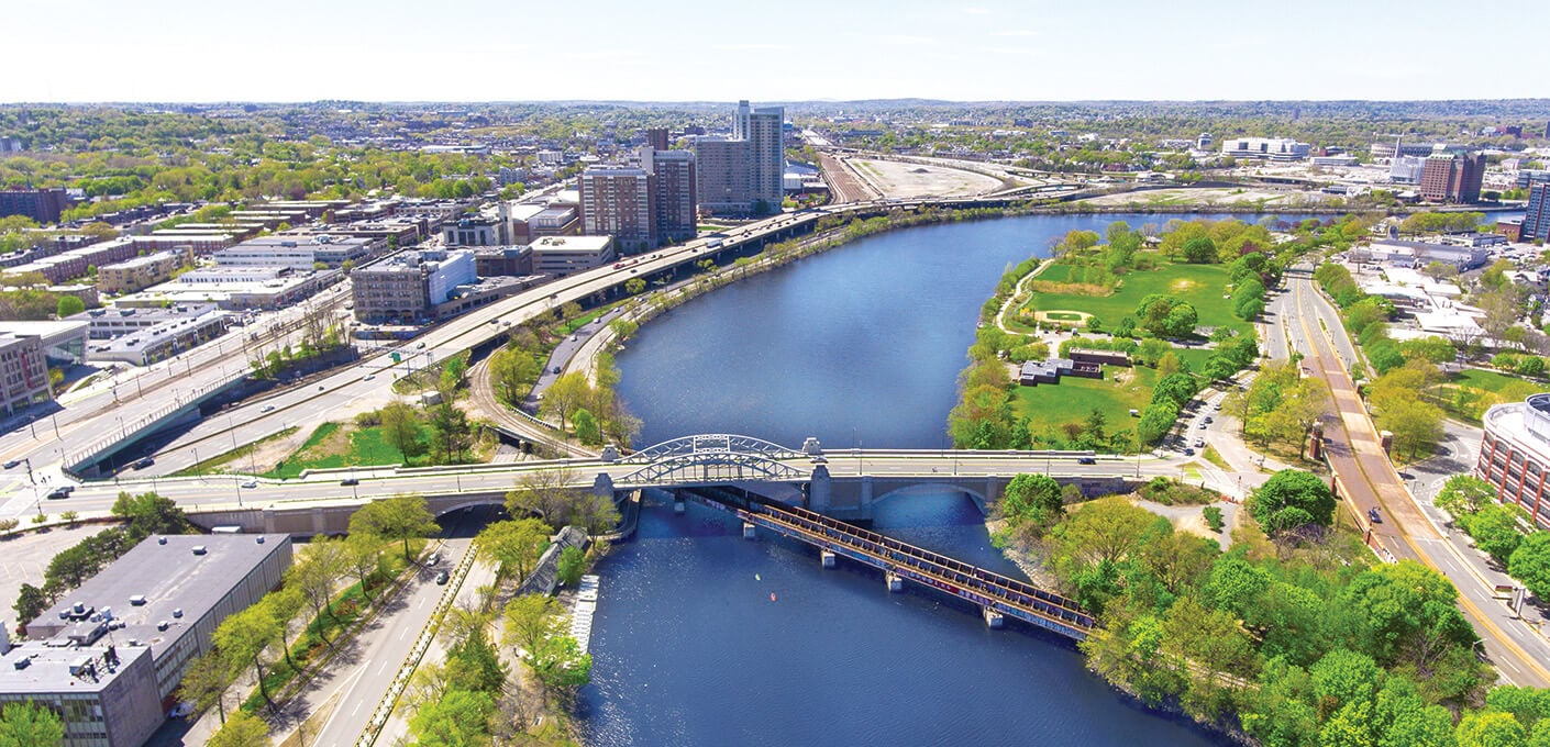 Aerial view of river, bridges, and green space in urban cityscape.