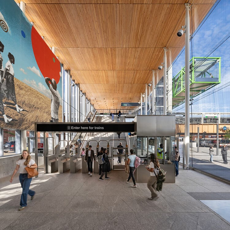 Modern train station entrance with colorful mural and passengers.