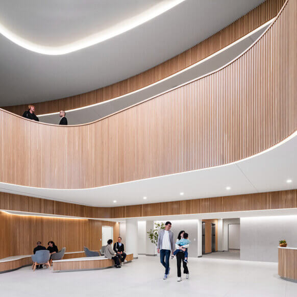 Modern lobby with wood accents, people walking and sitting in a stylish, open space.