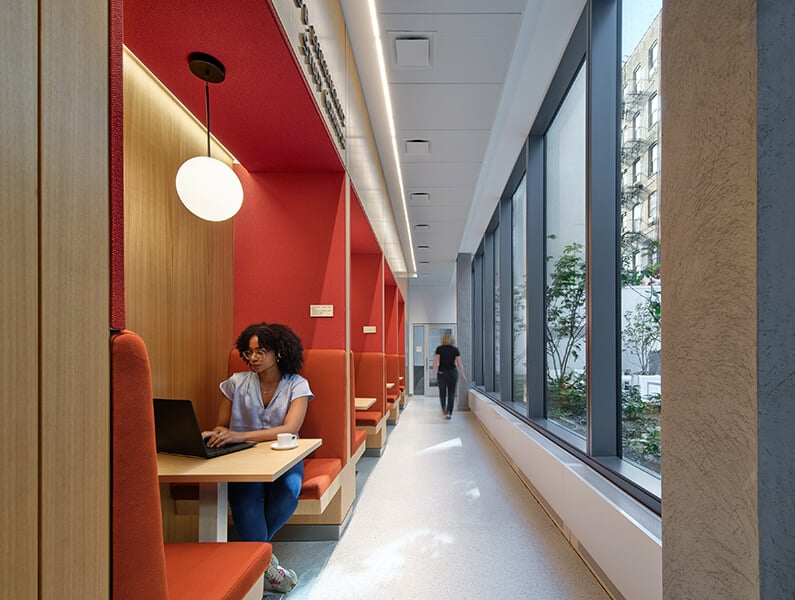Quiet student workspace with red booths and large windows.