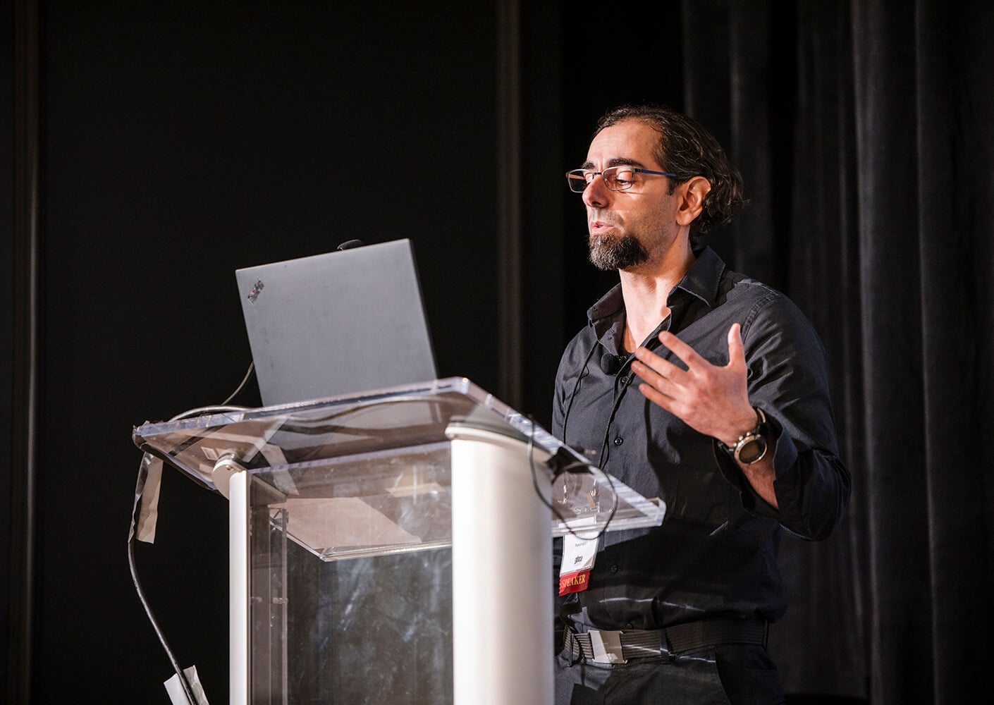Speaker presenting at a conference, gesturing passionately from the podium.