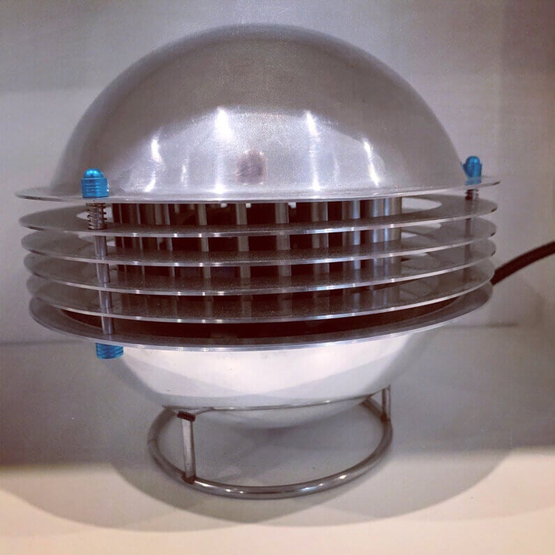 Stylish metallic fan with a dome shape and slatted design on a minimalistic base.