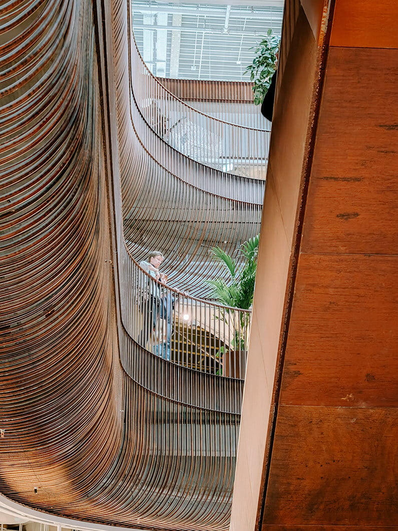 Elegant architectural staircase with curved railings and greenery. Modern interior design.