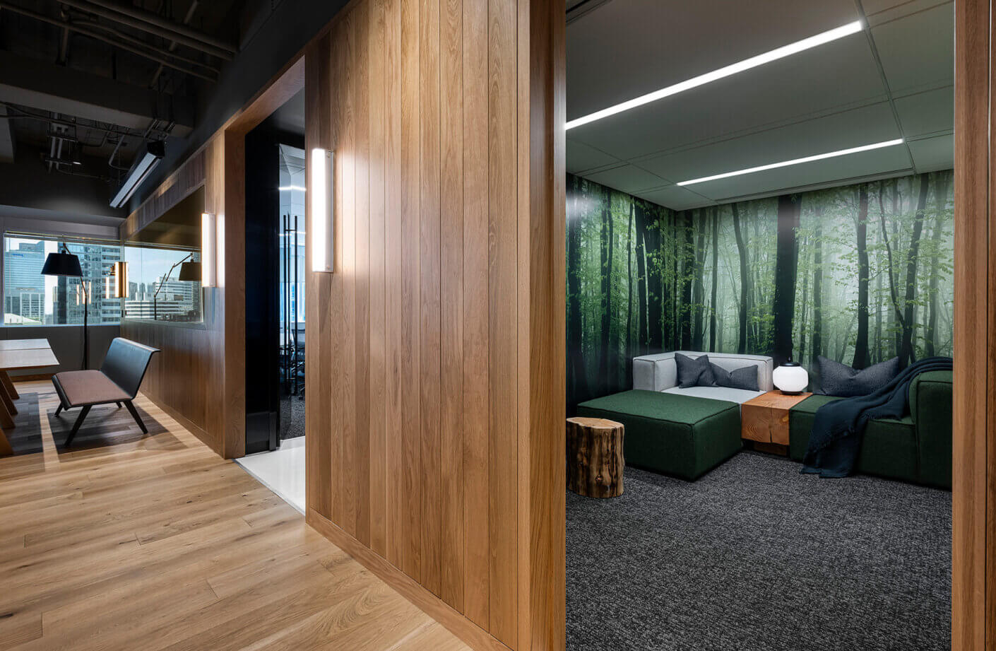 Interior view of an office space featuring wooden elements, a seating area with green tones, and a forest-themed room.