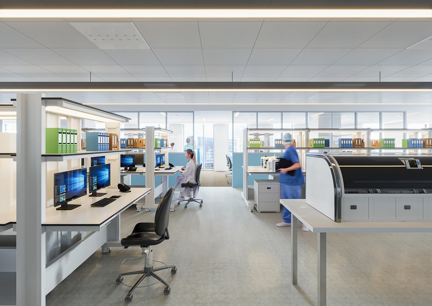 Open office space featuring workstations with computers and medical equipment, occupied by staff in lab coats and scrubs, against a bright backdrop.
