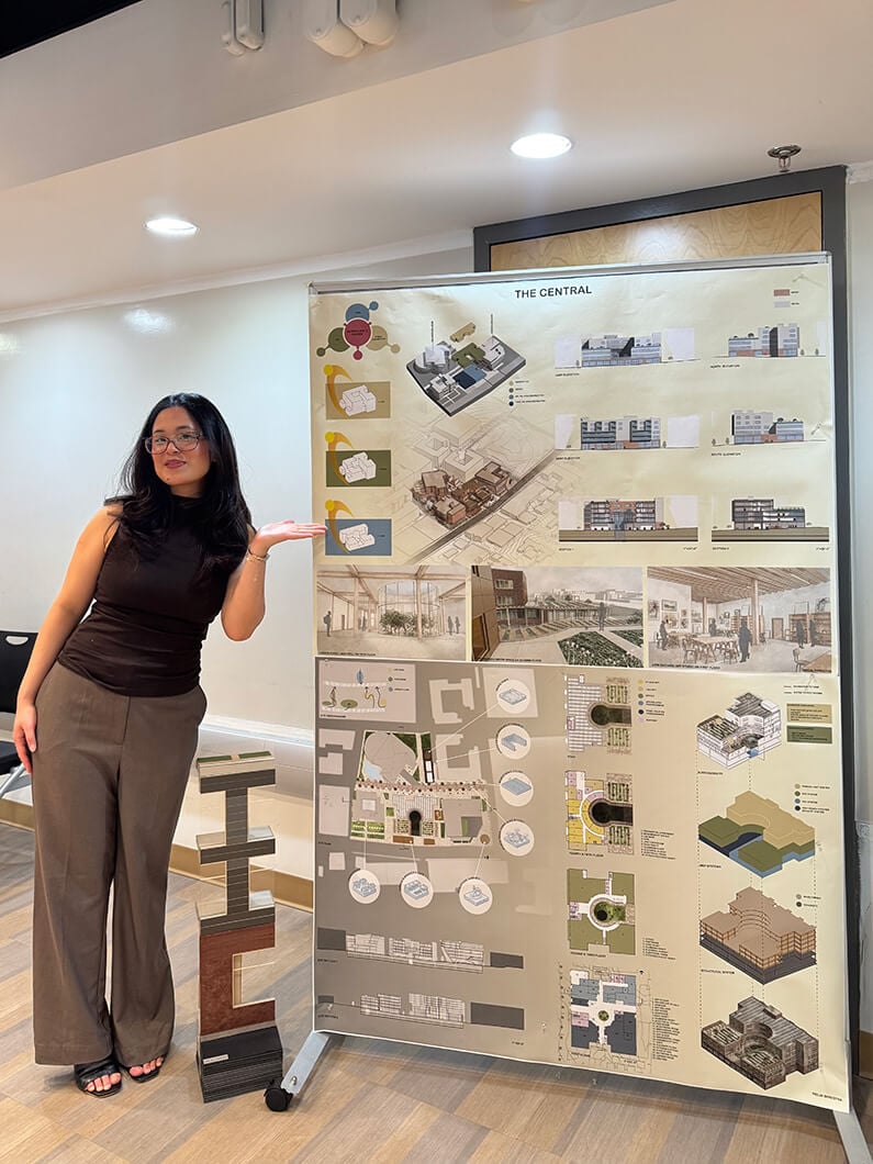 Person presenting an architectural project board titled The Central, showcasing design layouts and visual plans in an indoor setting.