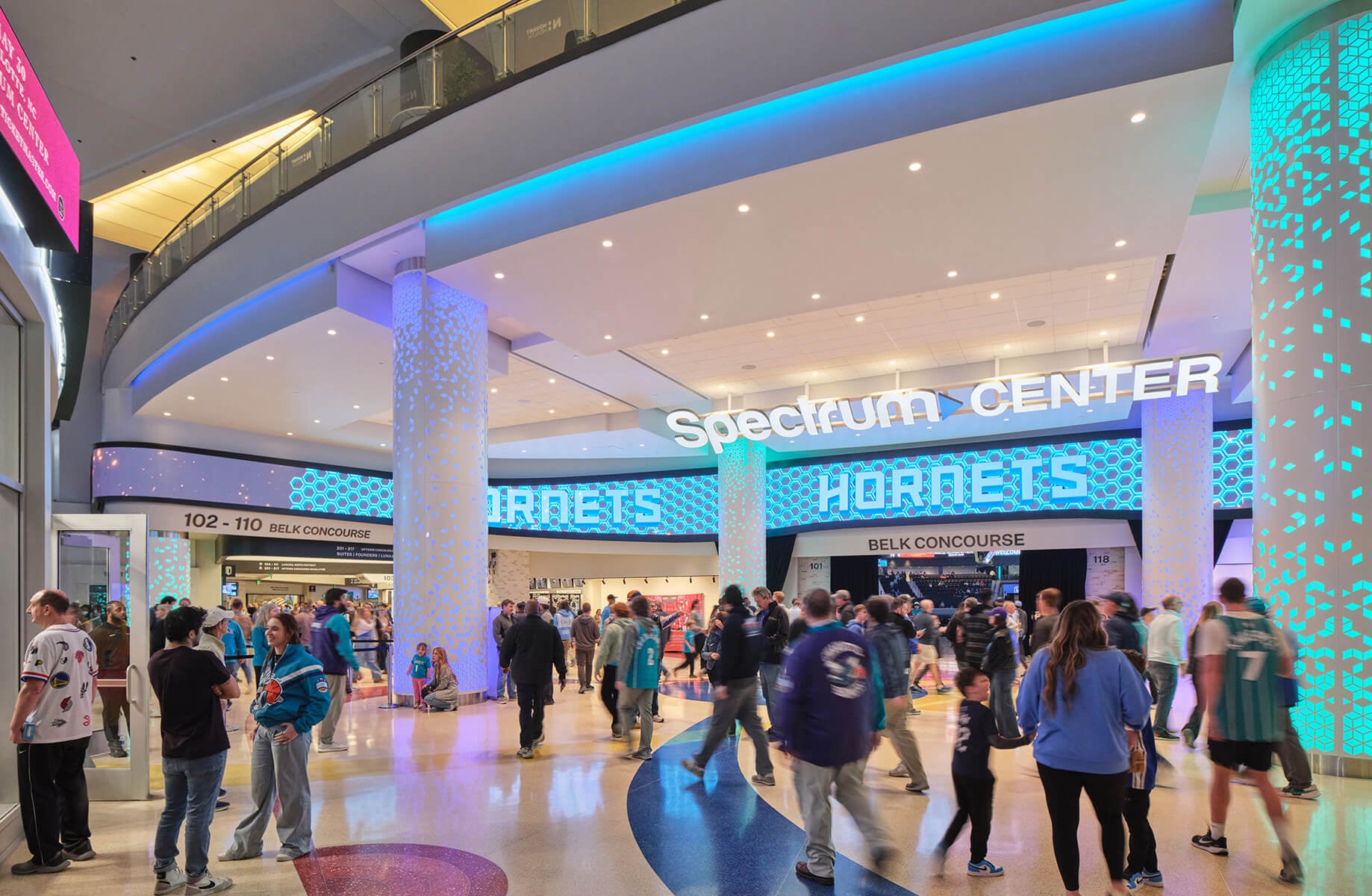 Crowd gathered at the Spectrum Center entrance with bright signage and illuminated pillars, showcasing an event atmosphere and sports enthusiasm.