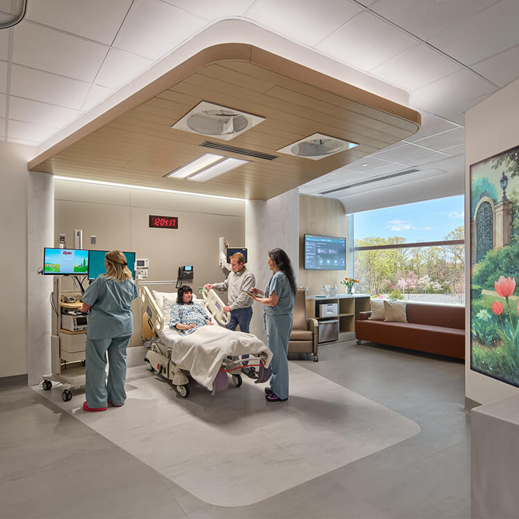 Healthcare professionals attend to a patient in a hospital room, featuring advanced medical equipment and a scenic view outside.