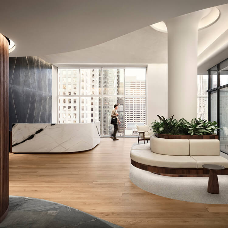 Interior office space with large windows, a reception desk, and a seating area featuring plants, wood accents, and natural light.